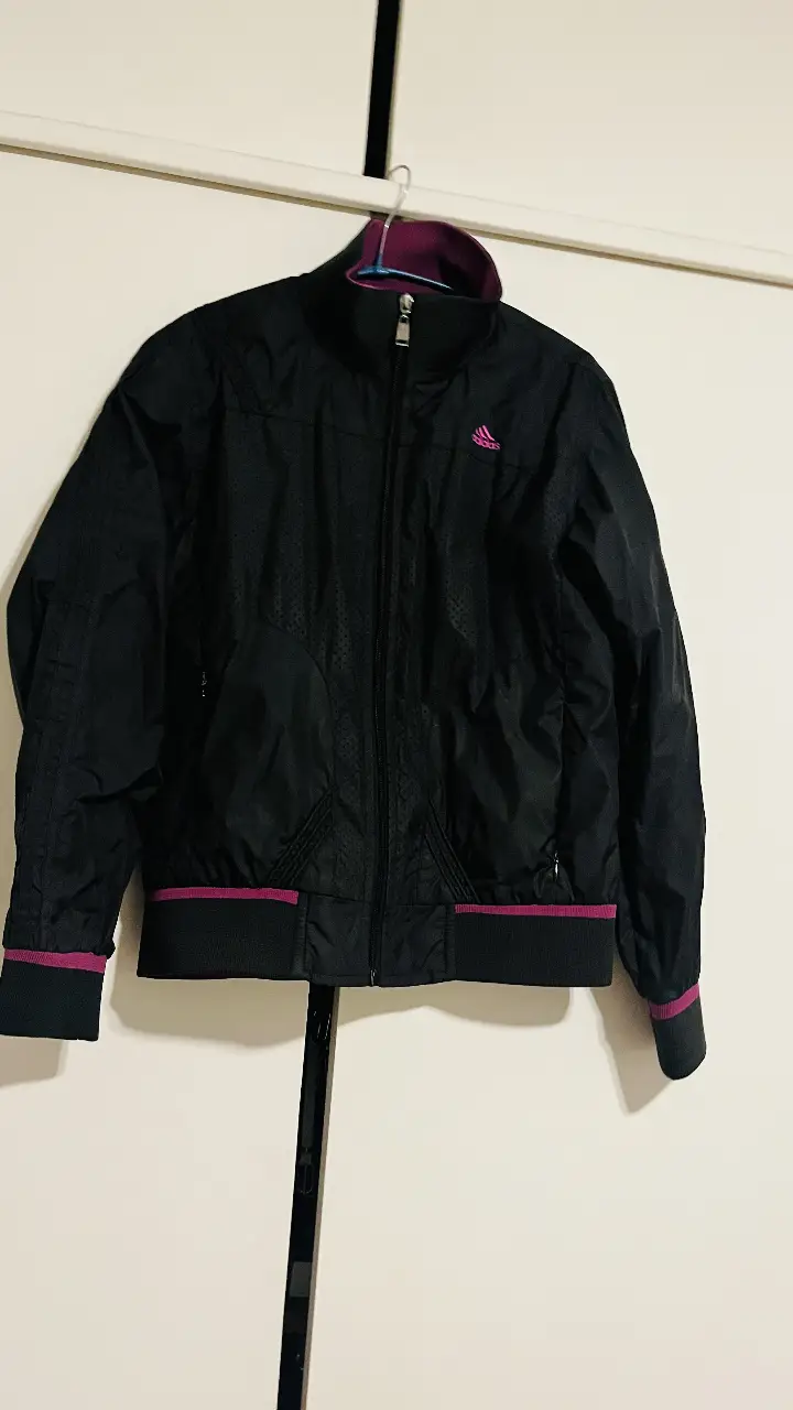 Campera deportiva Adidas climacool negra con detalles en violeta. Ideal para actividades al aire libre o para un look casual y cómodo. Cuenta con cierre y detalles perforados.