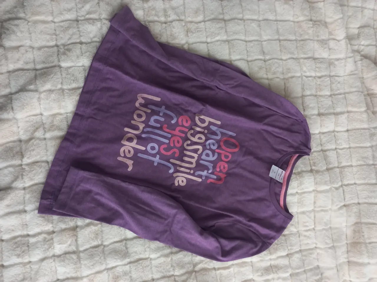 Remera de manga larga para niña, de color violeta con estampado. Tiene un diseño con frases en tonos rosas y blancos. Ideal para un look casual y cómodo.