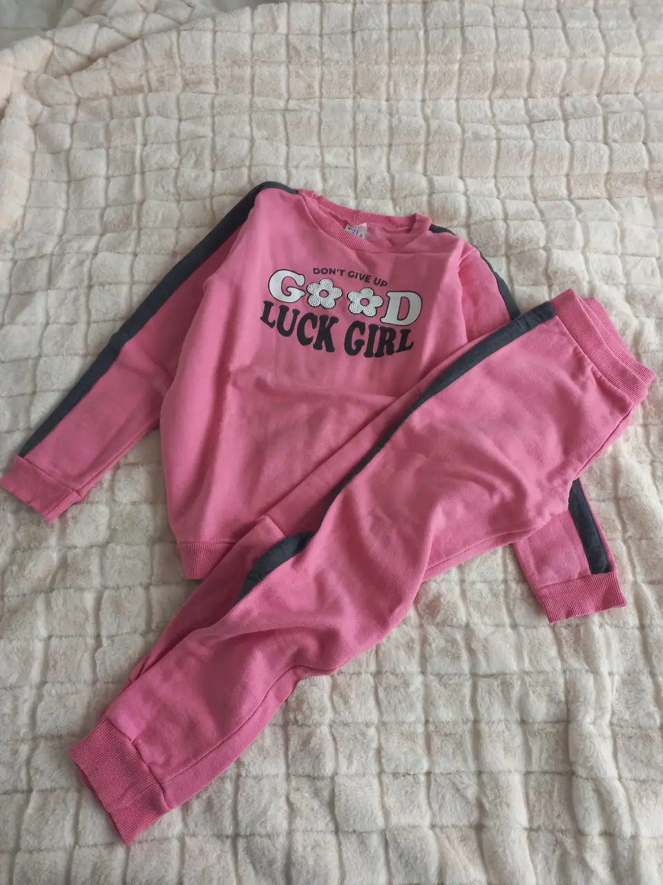 Conjunto deportivo de niña, color rosa con detalles en gris. El buzo tiene un estampado con la frase "GOOD LUCK GIRL". El pantalón es liso y a juego. Ideal para un look casual y cómodo.