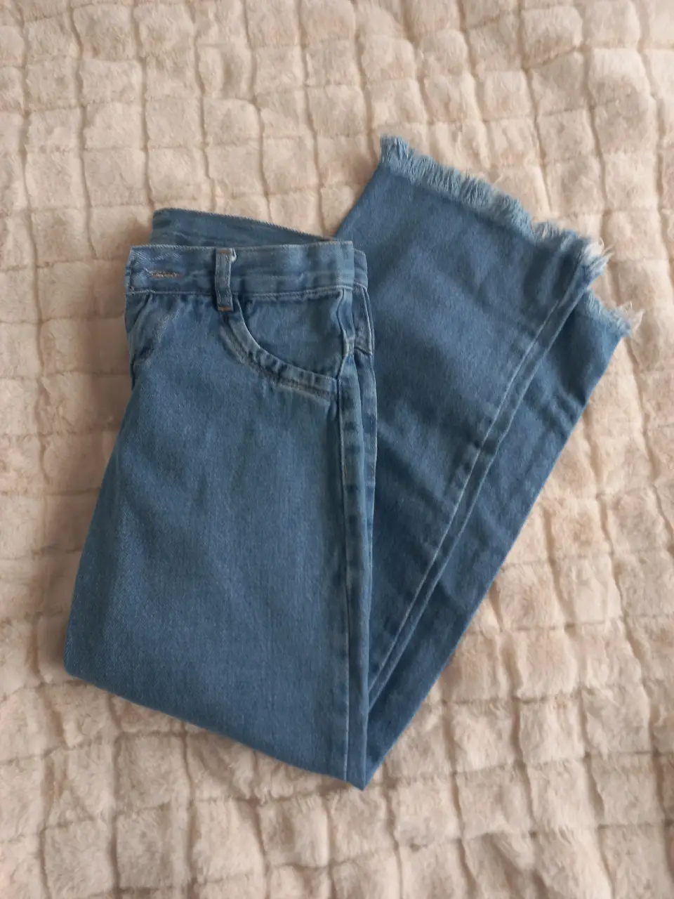 Jeans rectos de mujer, color azul claro, con detalle de flecos en el borde inferior. Talle 12.