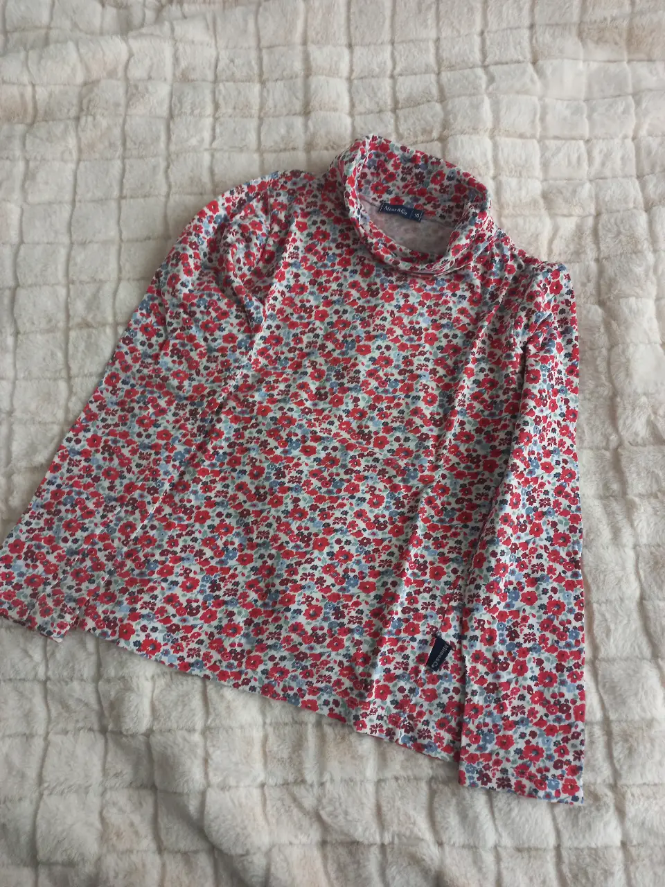 Remera de manga larga para niña, con cuello alto y estampado floral en tonos rojos y azules sobre fondo blanco. Marca Mimo & Co, talle 10.