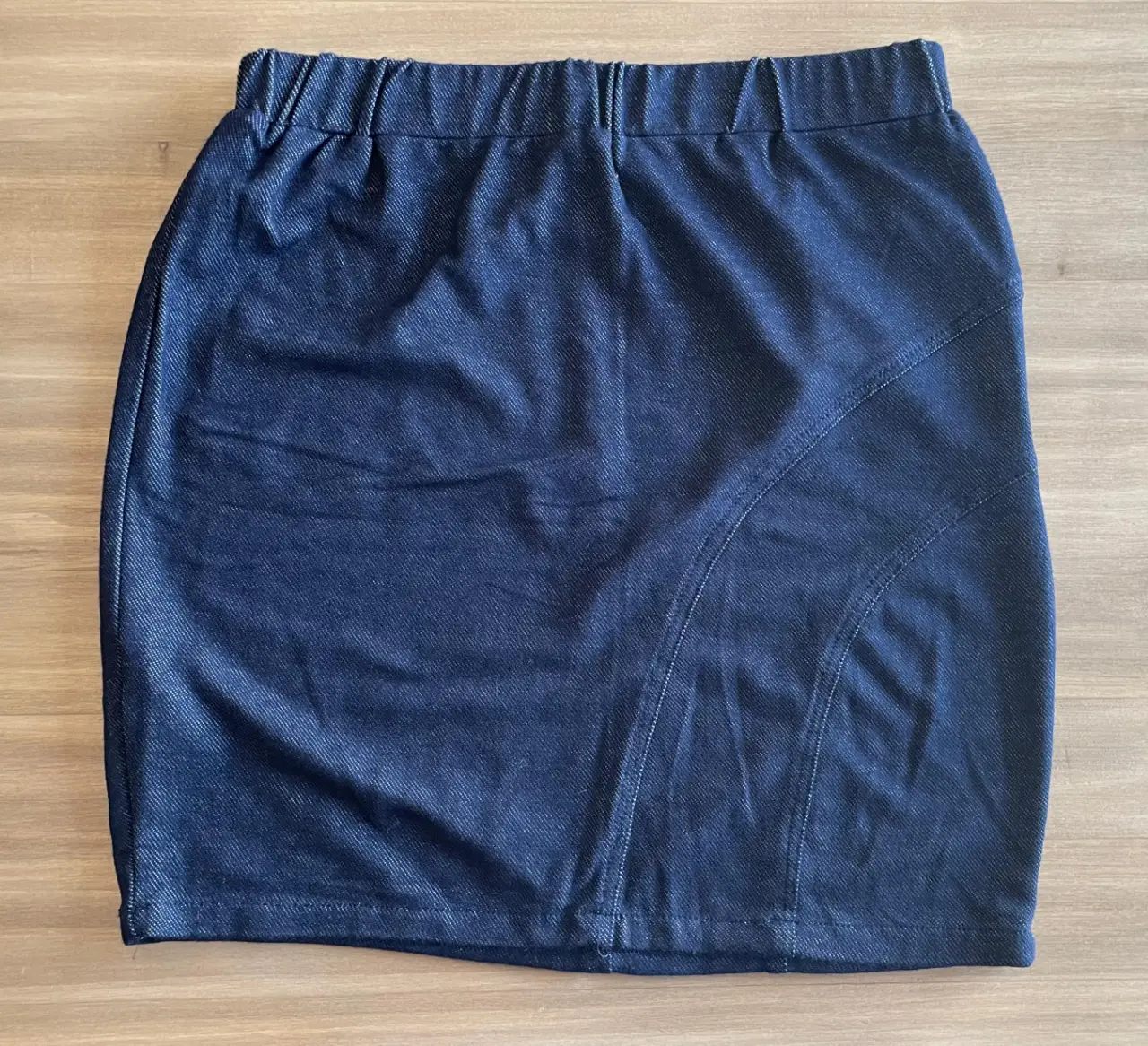 Pollera de jean azul oscuro, con cintura elastizada y detalle de costuras diagonales. Ideal para un look casual y cómodo. 32 cm cintura, 38 cm Largo.