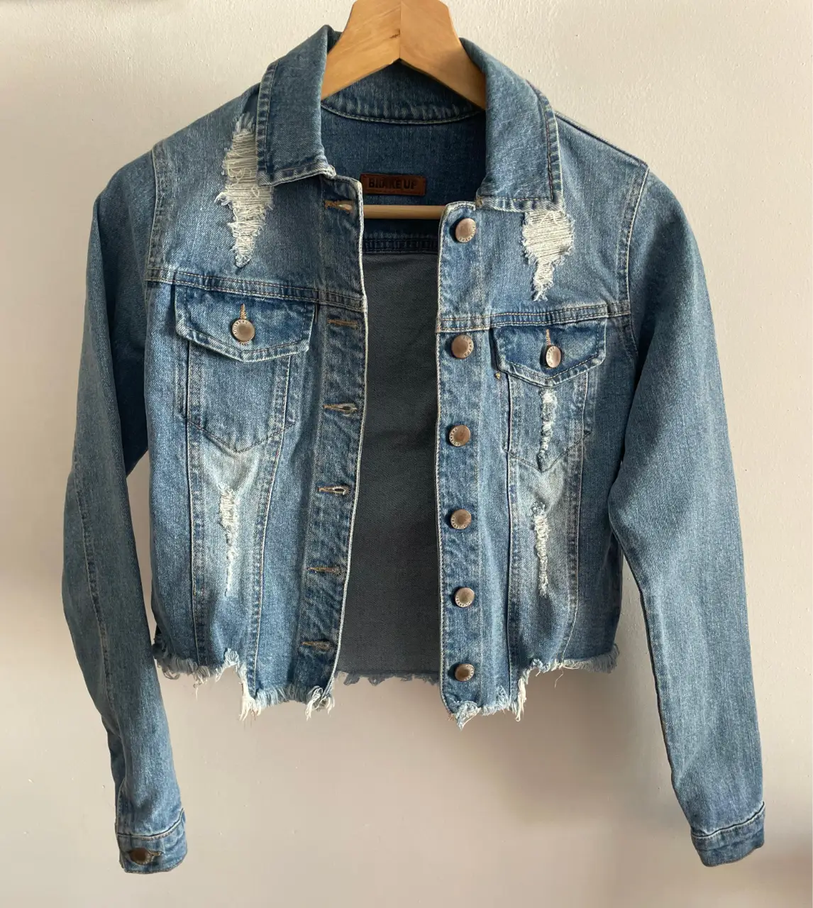 Campera de jean azul claro con detalles rotos y flecos en el borde inferior. Marca Brake Up, talle 1. Sisa 40 cm, 45 cm largo, 57 cm mangas.