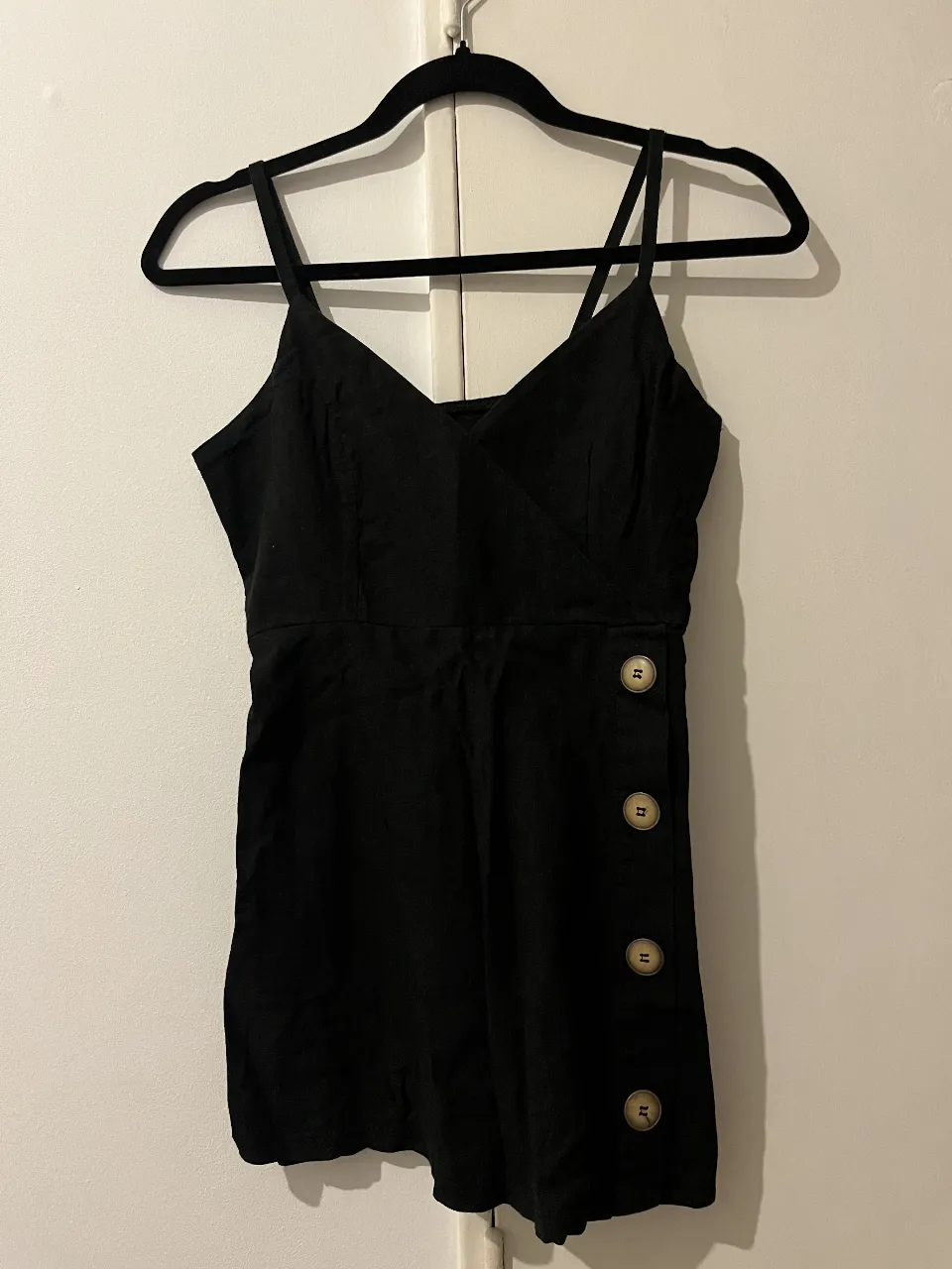 Vestido negro corto con breteles finos y detalle de botones en el lateral. Ideal para un look casual o para salir.