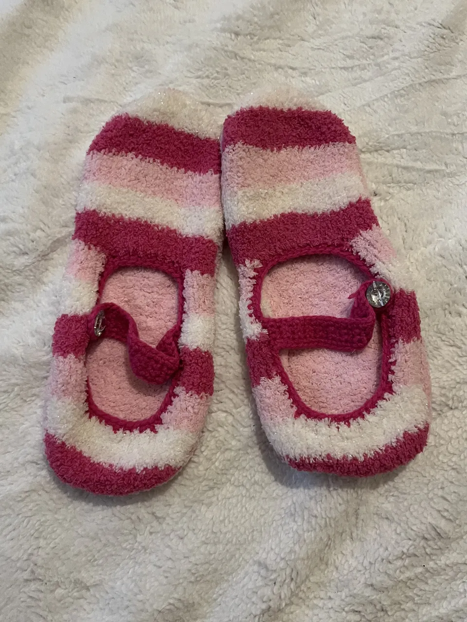 Pantuflas súper tiernas y cómodas a rayas rosas, blancas y fucsia. Tienen un detalle de moño y brillito en la tira. Ideales para estar calentita en casa.