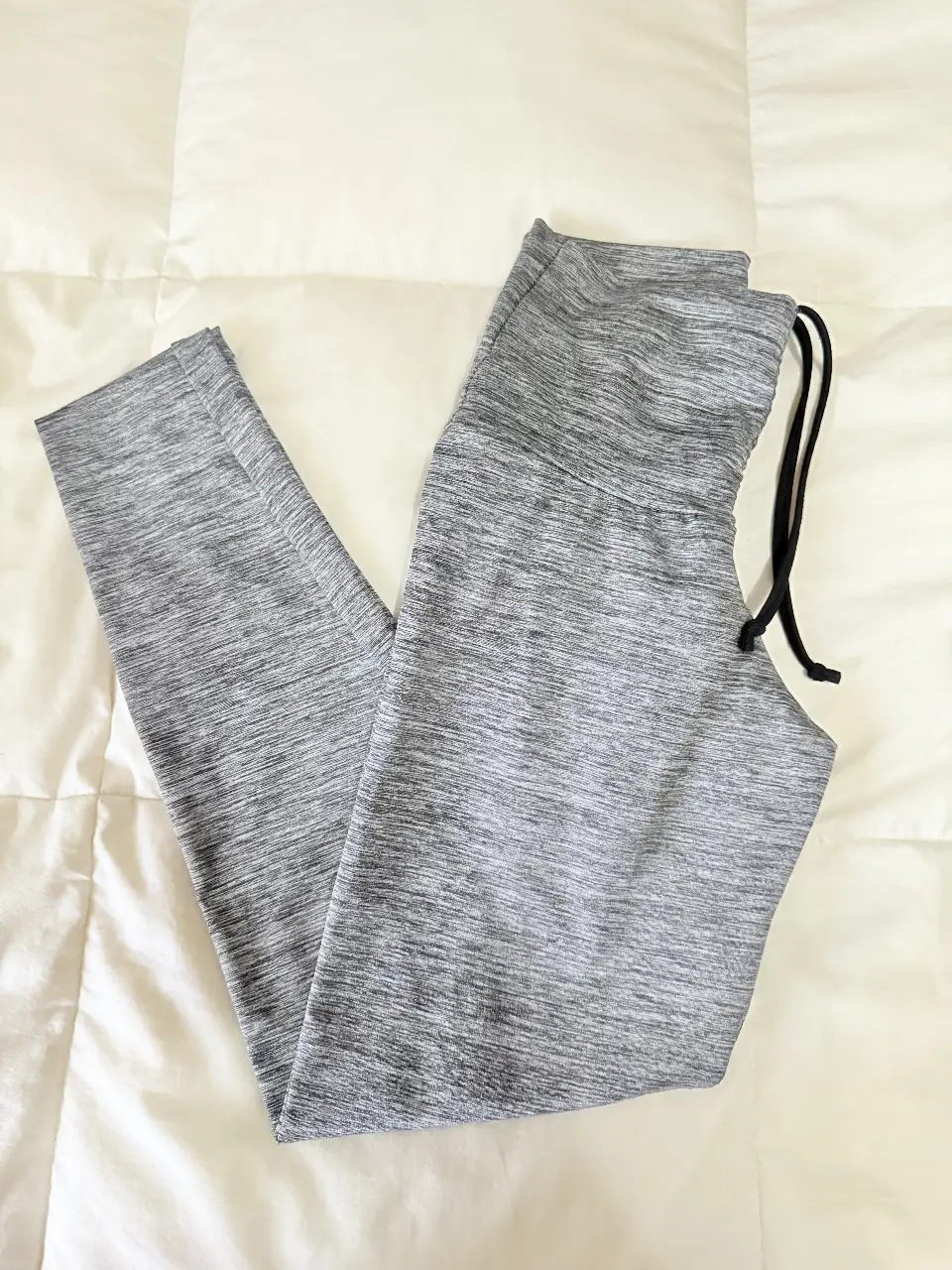 Calzas deportivas grises con cintura alta y detalle fruncido en la parte trasera. Ideal para entrenamientos y actividades físicas.