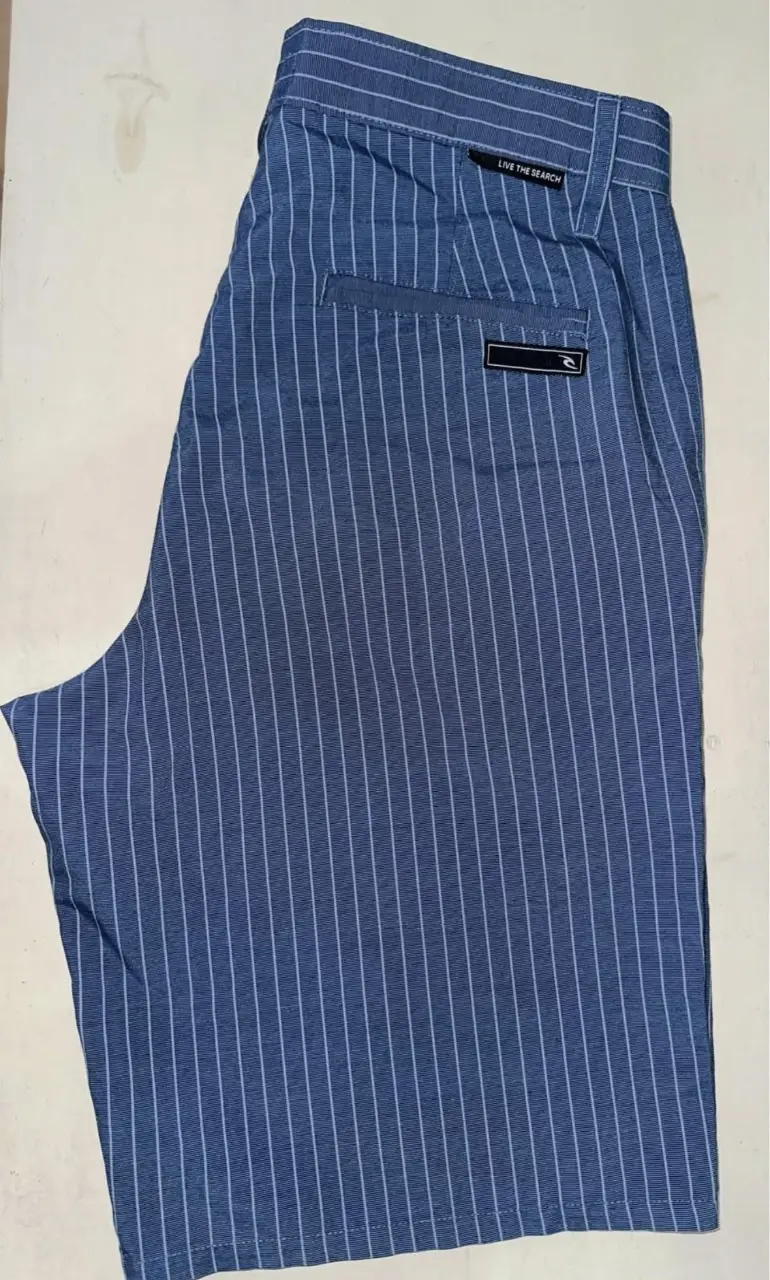 Short de hombre con diseño a rayas verticales en color azul y blanco. Posee bolsillos delanteros y traseros, y un detalle de etiqueta con logo en la parte trasera. Ideal para un look casual y fresco.