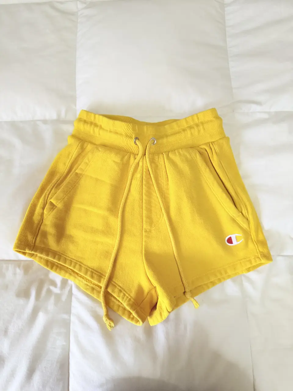 Short deportivo amarillo de la marca Champion, ideal para actividades físicas o para un look casual y cómodo. Confeccionado en tela suave y con el logo de la marca.
