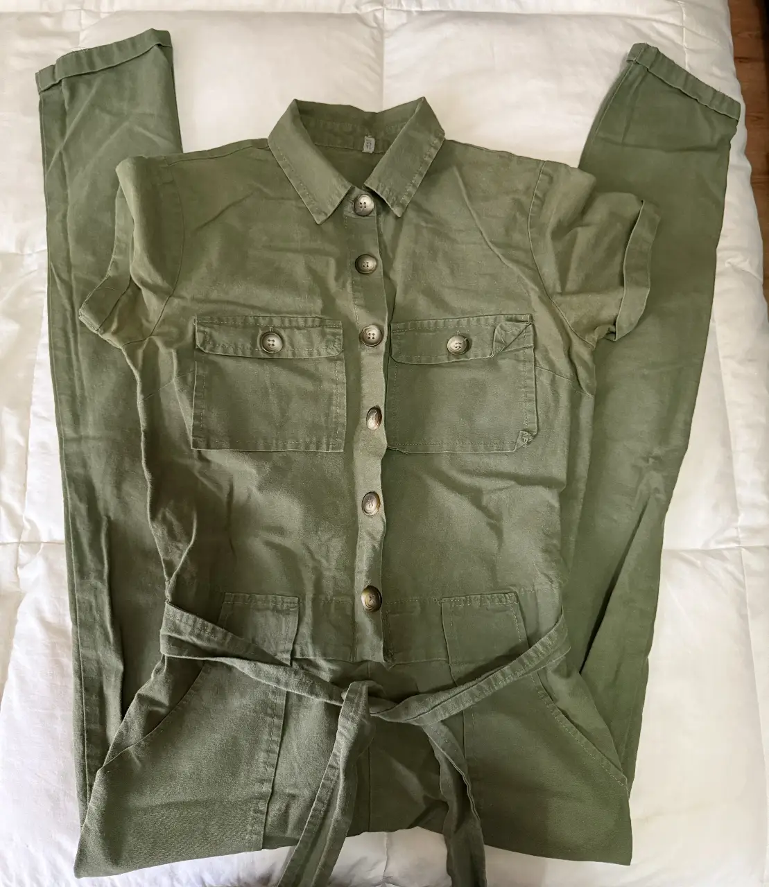 Mono largo de color verde militar, con mangas cortas y cinturón para ajustar la cintura. Posee bolsillos delanteros y botones frontales. Ideal para un look casual y cómodo.