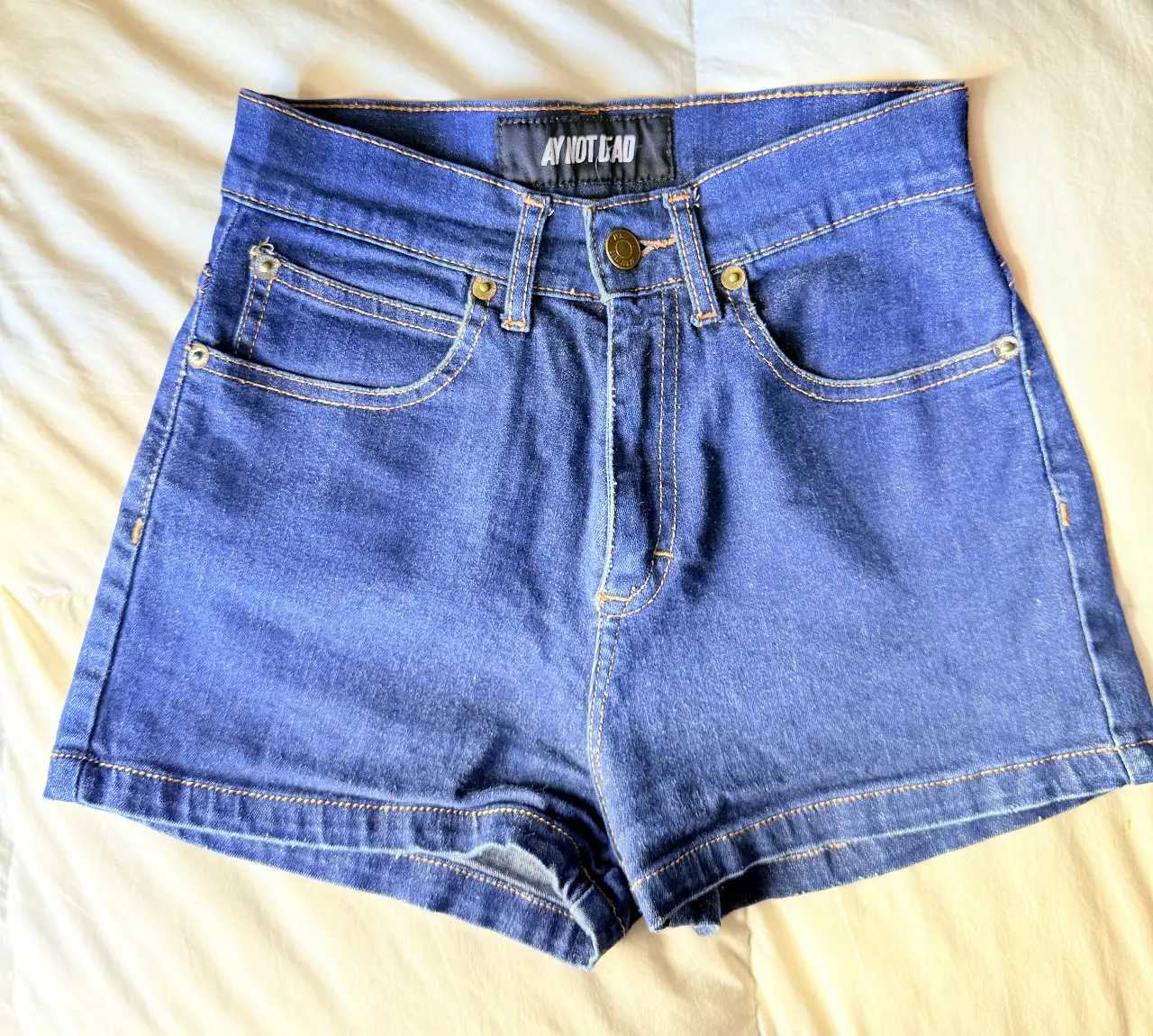 Short de jean azul de tiro alto, con bolsillos delanteros y traseros. Ideal para un look casual y moderno.