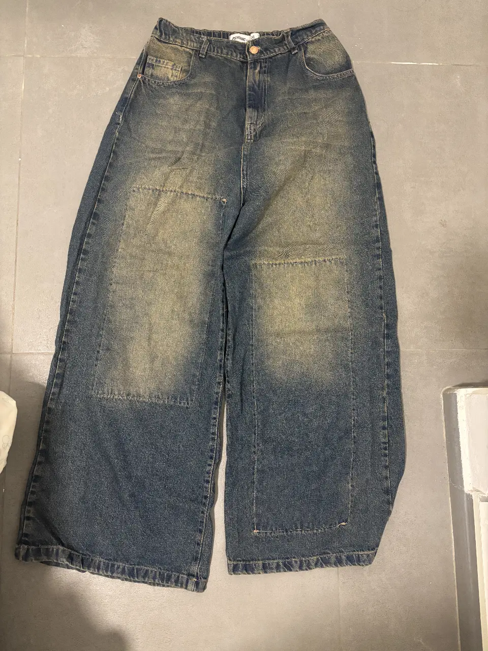 Jeans oversize de hombre, tiro alto, con efecto gastado y parches en las rodillas. Talle 36, marca Psychic Denim. Ideal para un look urbano y relajado.