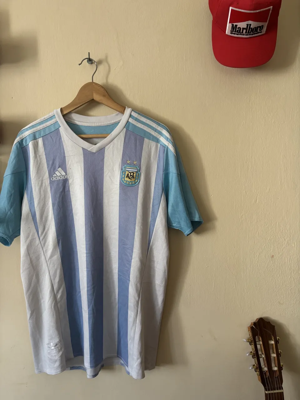 Remera de fútbol a rayas verticales blancas y celestes. Escudo de la AFA y logo de Adidas en el frente. Mangas cortas y cuello redondo. Muchos detallea.