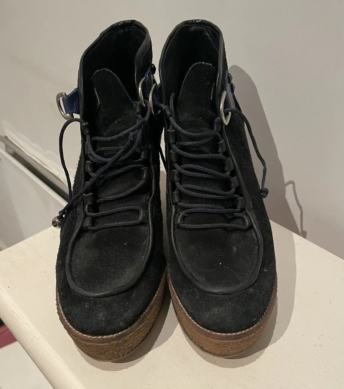 Botines de gamuza negros con detalles en cuero azul y suela de madera. Ideales para un look casual y moderno.
