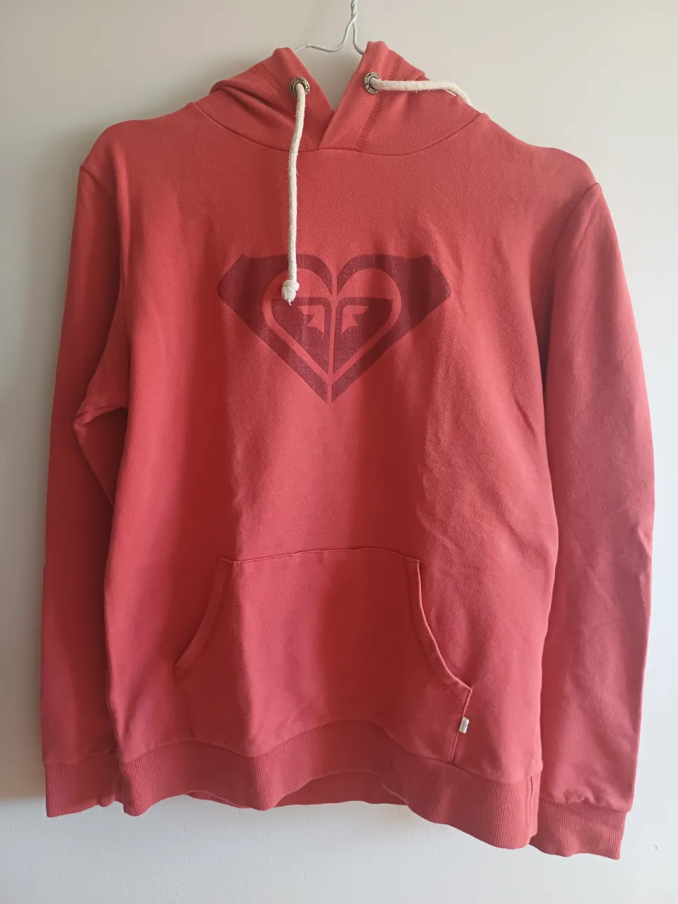 Buzo de color rojo, con capucha y bolsillo. Esta casi como nuevo, se puede ver unas pequeñas imperfecciones en el estampado.