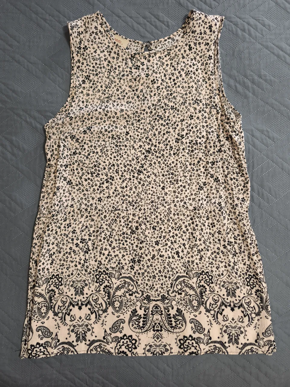 Musculosa súper fresca y liviana con un delicado estampado floral en crudo y negro. Posee un detalle de paisley en la parte inferior que le da un toque bohemio y chic. Ideal para los días cálidos, para usar en la playa, en una salida casual o simplemente para estar cómoda en casa.