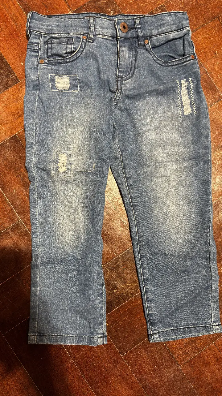 Jean azul para niña con detalles rotos y parches. Talle 4. Ideal para un look casual y moderno.