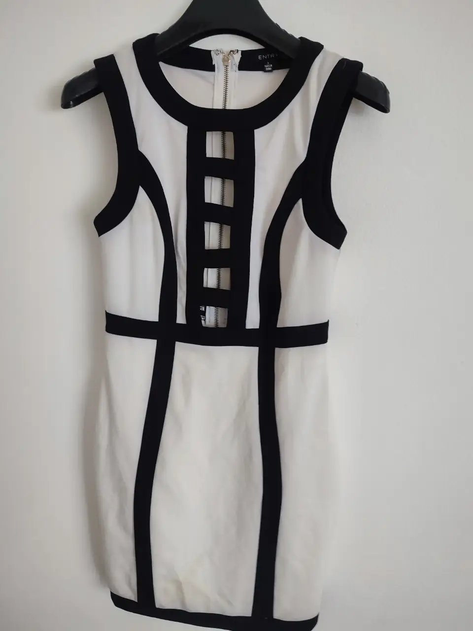 Vestido mini blanco con detalles en negro. Diseño con cierre en el frente y detalles geométricos. Ideal para una salida o fiesta.