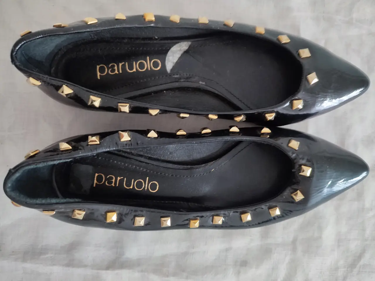 Ballerinas negras de charol con tachas doradas, ideales para un look elegante y moderno. Perfectas para cualquier ocasión.