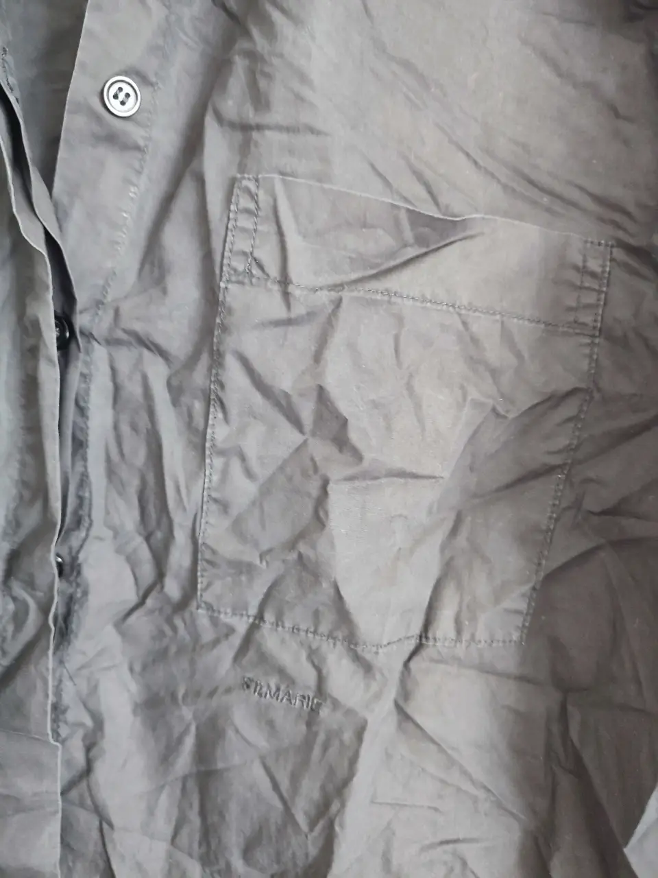 Camisa de mujer negra, con bolsillo en el pecho y etiqueta de la marca. Ideal para un look casual y versátil.