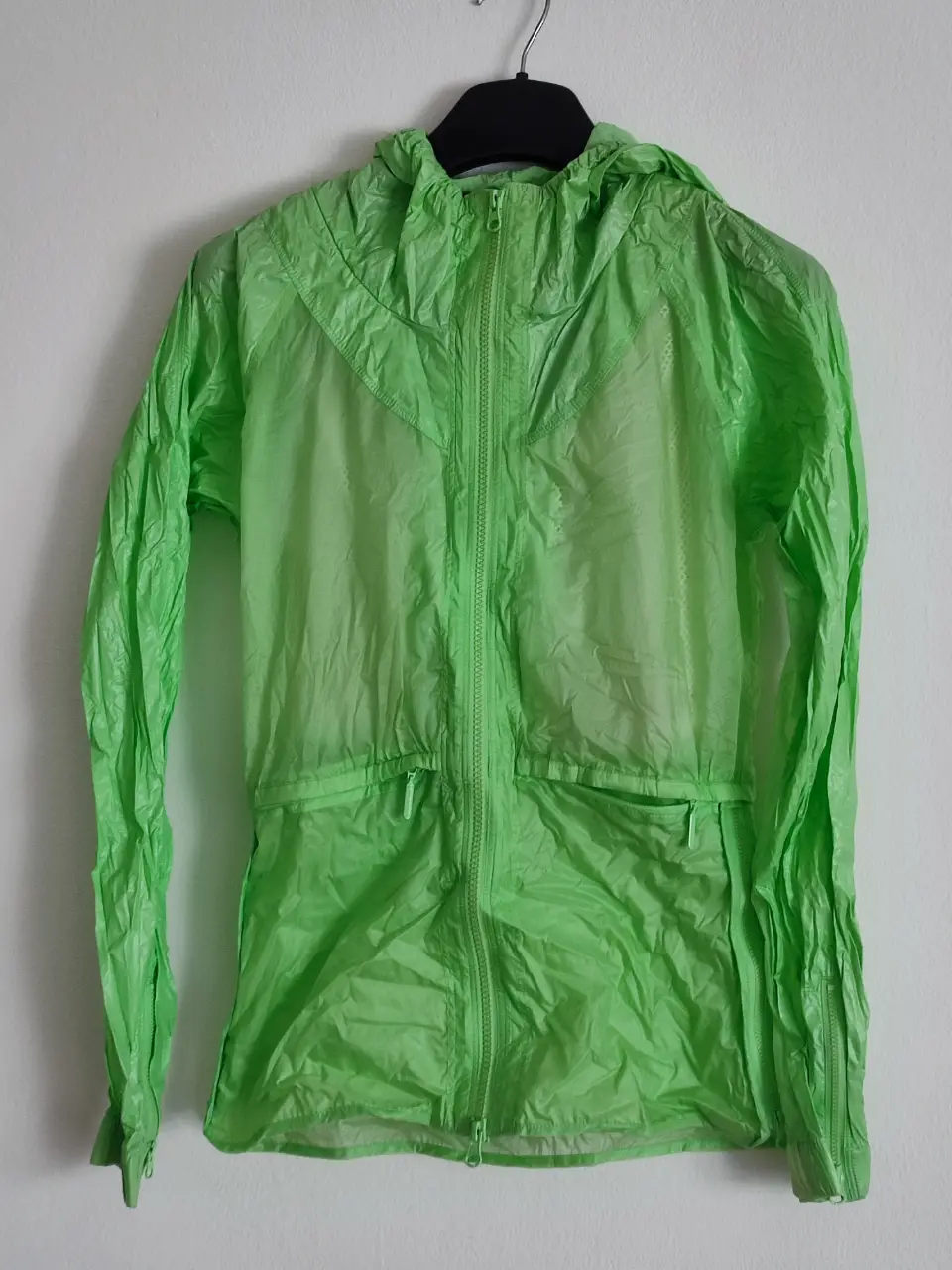 Campera rompevientos verde lima de la marca Stella McCartney para Adidas. Con capucha y cierre frontal. Ideal para actividades deportivas o para un look casual.