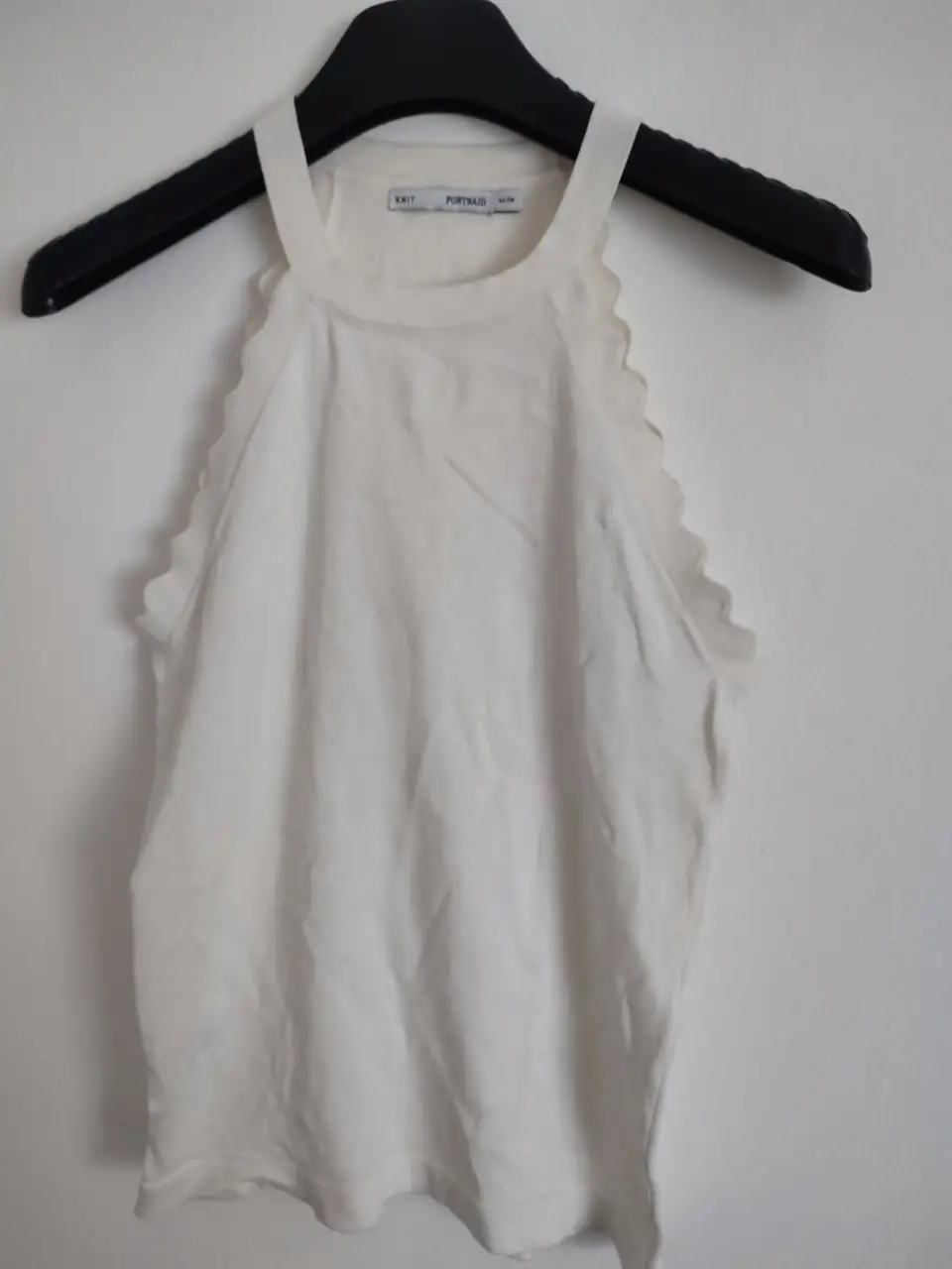 Top blanco con detalle de volados en el cuello y sisas. Ideal para un look fresco y moderno.