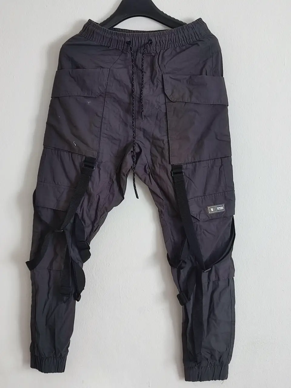 Pantalón cargo de hombre, color gris oscuro. Diseño utilitario con múltiples bolsillos y correas ajustables. Ideal para un look streetwear y funcional.