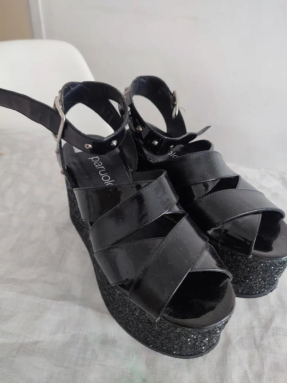 Sandalias de plataforma negras con detalles brillantes y tiras cruzadas. Ideales para darle un toque moderno y audaz a tus looks de fiesta.