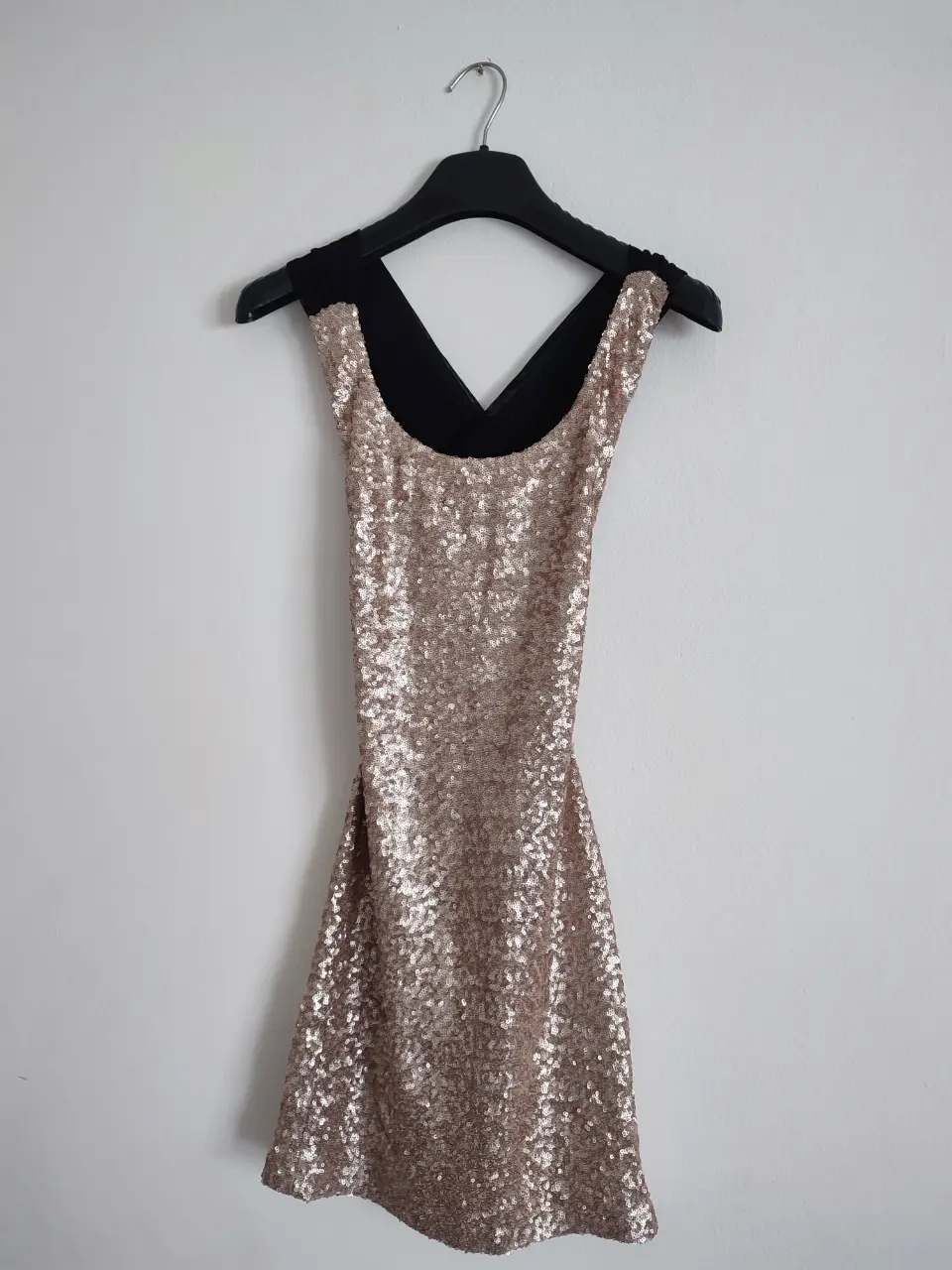 Vestido mini de fiesta con lentejuelas doradas y espalda cruzada en negro. Ideal para eventos especiales y salidas nocturnas.
