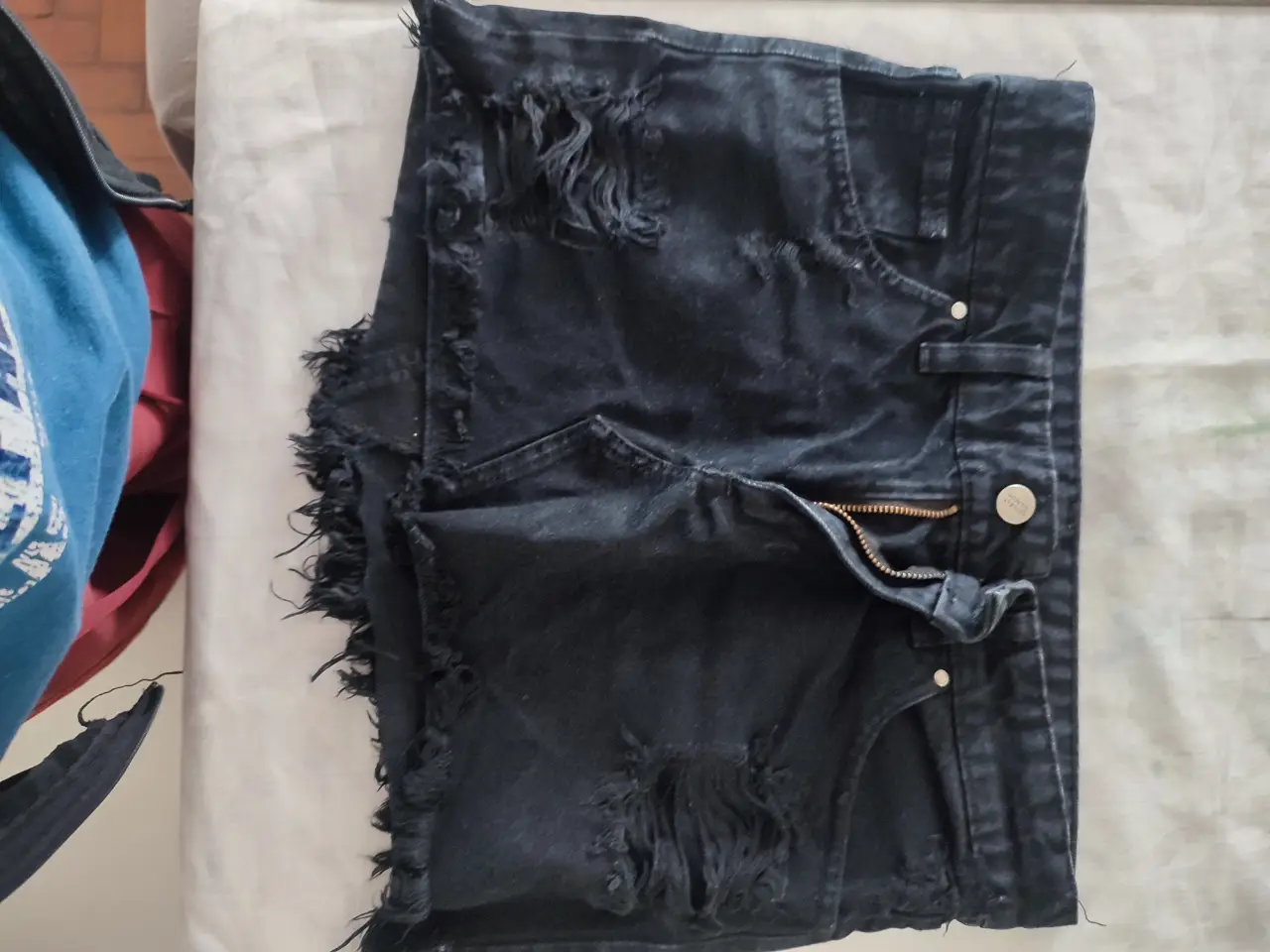 Short de jean negro con detalles rotos y desflecado. Talle 24, ideal para un look casual y moderno.