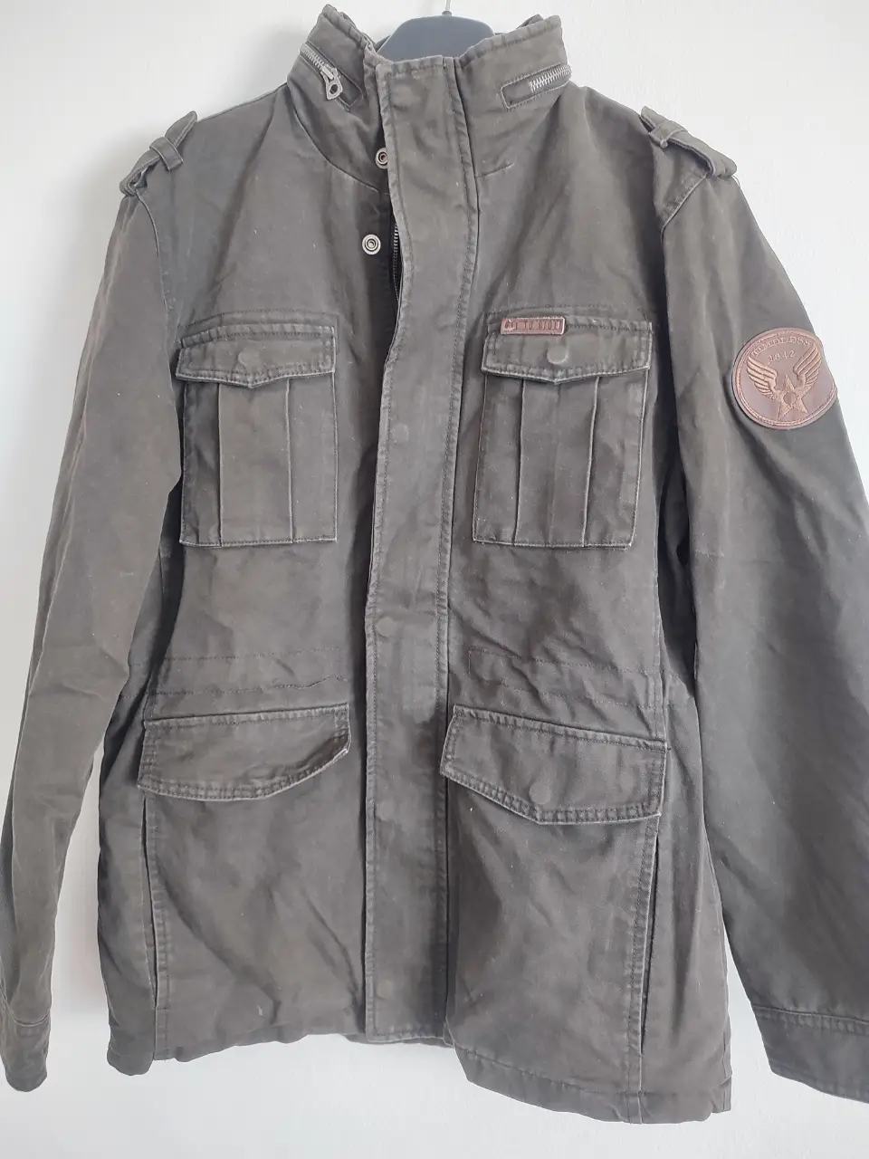 Campera tipo casadora de hombre, color verde oscuro, con forro interno de abrigo. Posee múltiples bolsillos y detalles de diseño. Marca Old Bridge, talle L.