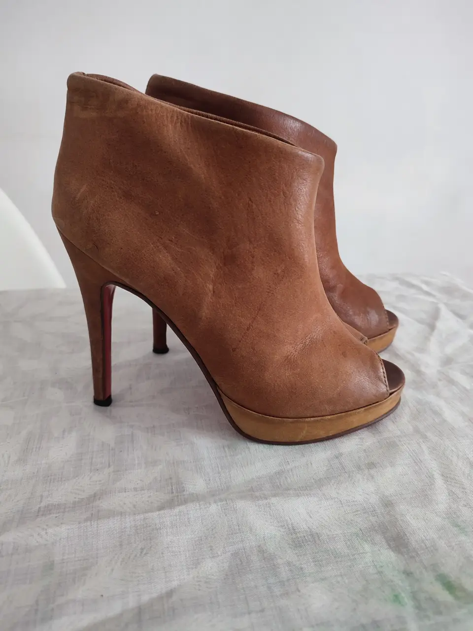 Botines de cuero marrón con taco alto y suela roja. Diseño elegante y sofisticado, ideales para ocasiones especiales.