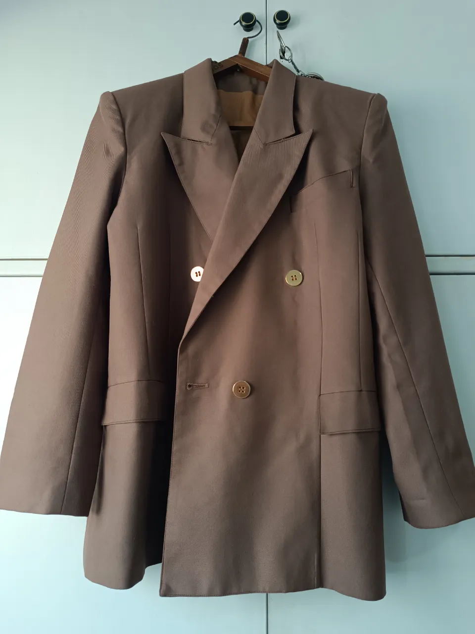 Elegante blazer marrón de corte clásico, ideal para un look formal o de trabajo. Confeccionado con un tejido de calidad, este blazer de mujer presenta un diseño de doble botonadura y bolsillos funcionales. Perfecto para combinar con pantalones sastreros o faldas.