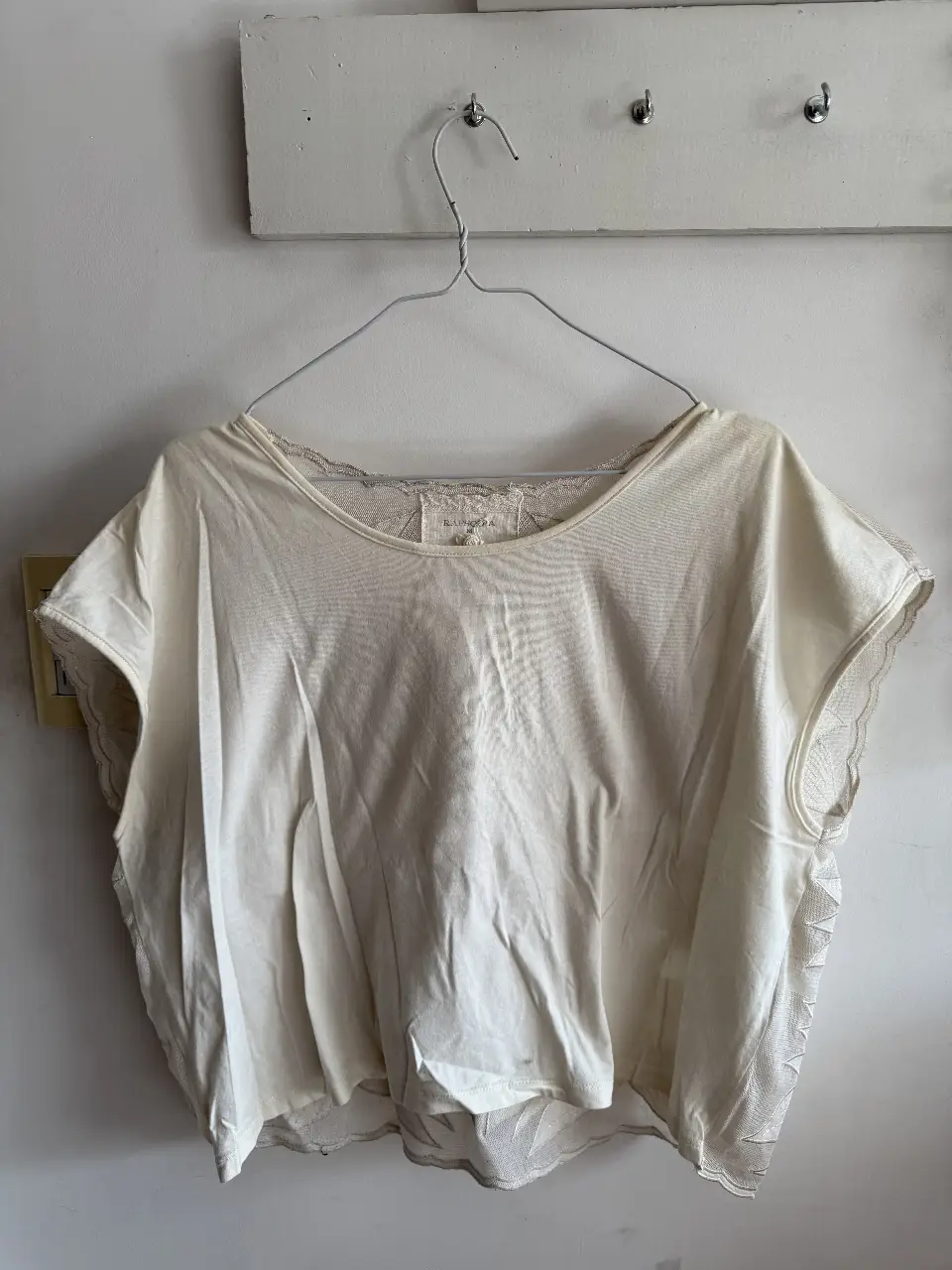 Blusa de encaje color blanco roto, con mangas cortas y detalles de encaje en los bordes. Ideal para un look elegante y fresco.