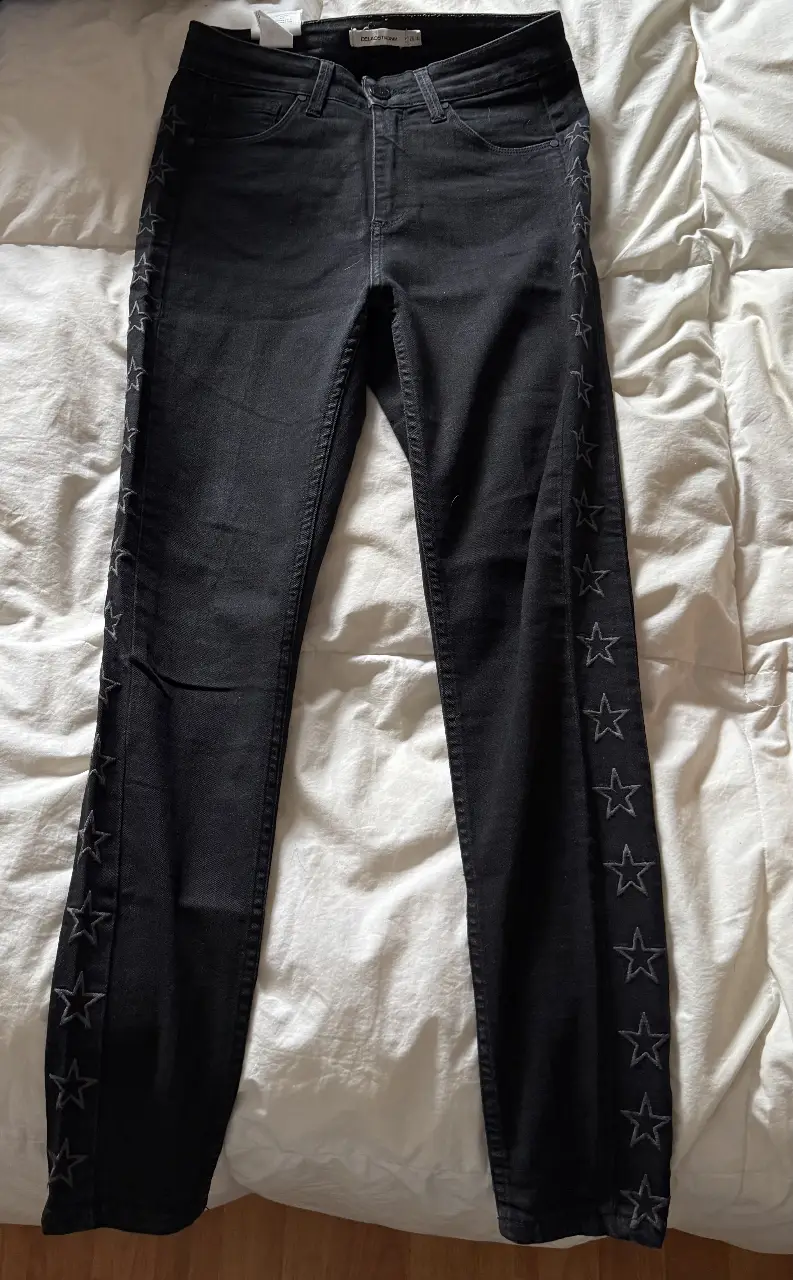 Jeans negros de tiro alto con detalles de estrellas en los laterales. Corte recto, ideal para un look casual y moderno.
