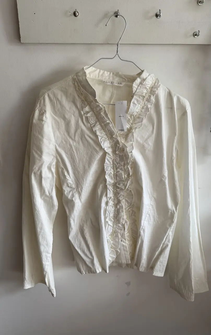 Blusa blanca con detalles de volados y encaje. Ideal para un look elegante y romántico.