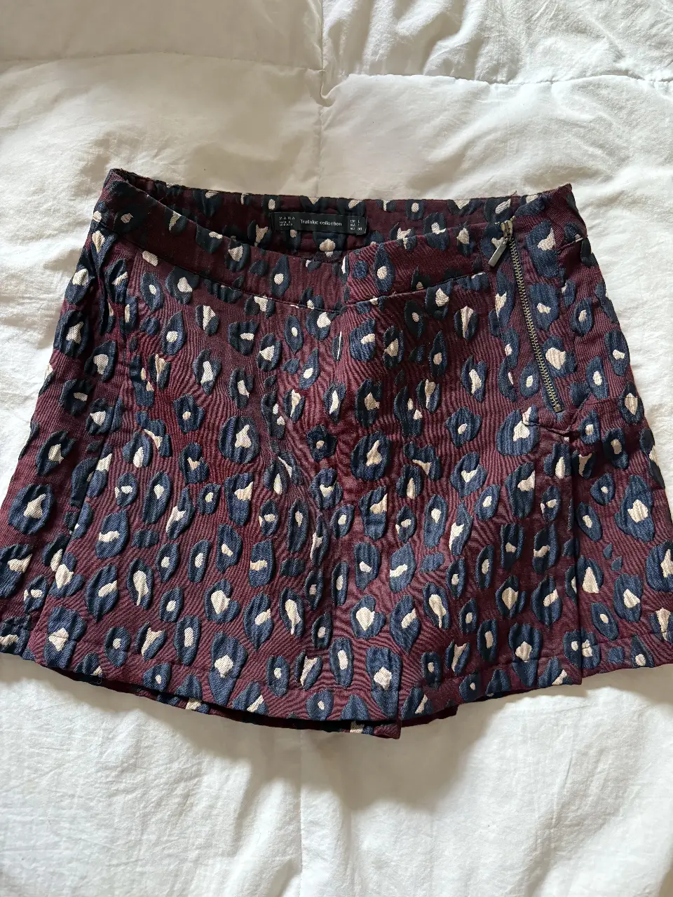 Short pollera de mujer con estampado de leopardo en tonos borgoña y azul marino. Diseño con cierre lateral y detalles plisados. Ideal para un look moderno y audaz.