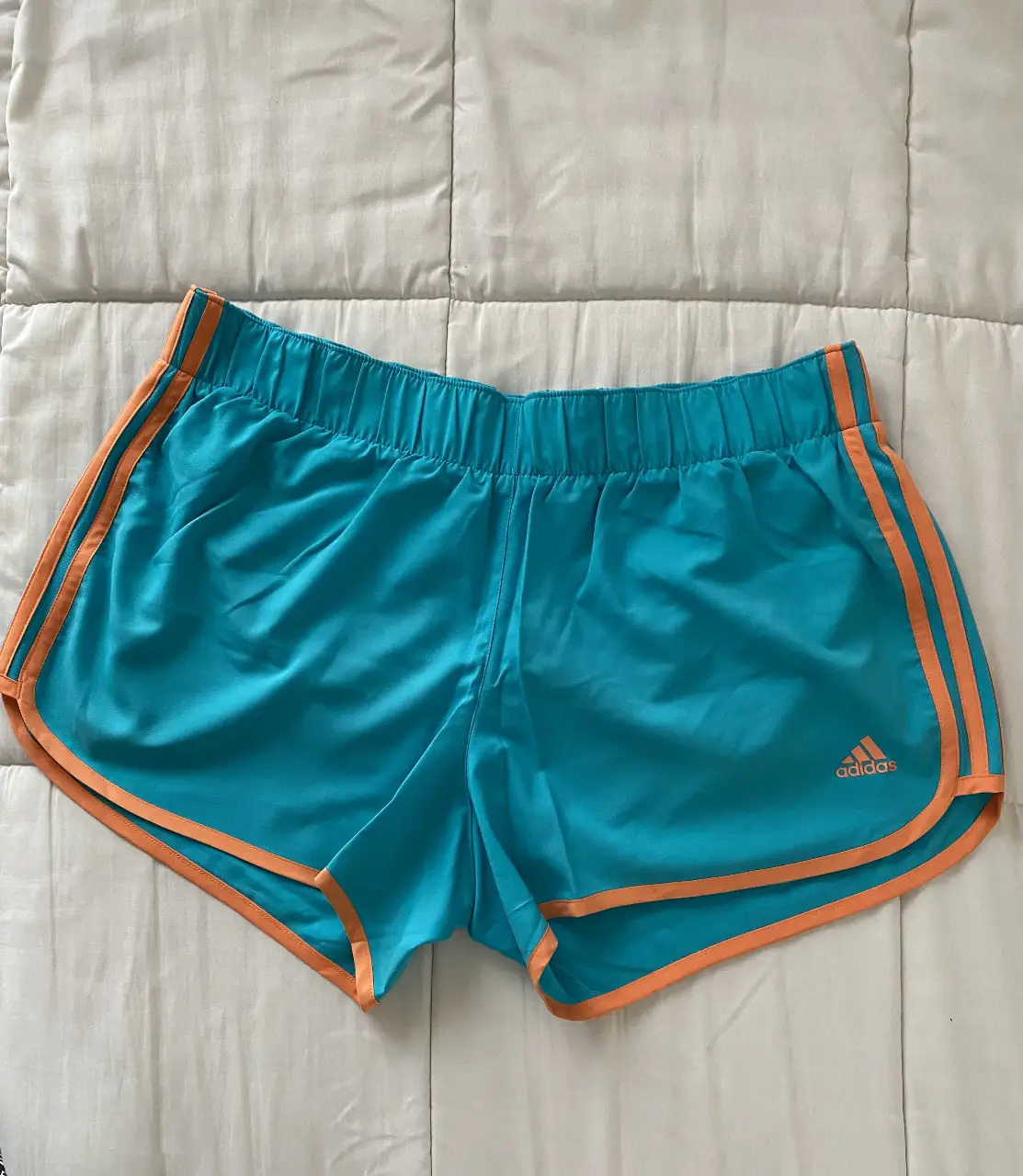 Short deportivo Adidas original de mujer, color turquesa con detalles en naranja. Ideal para actividades físicas.