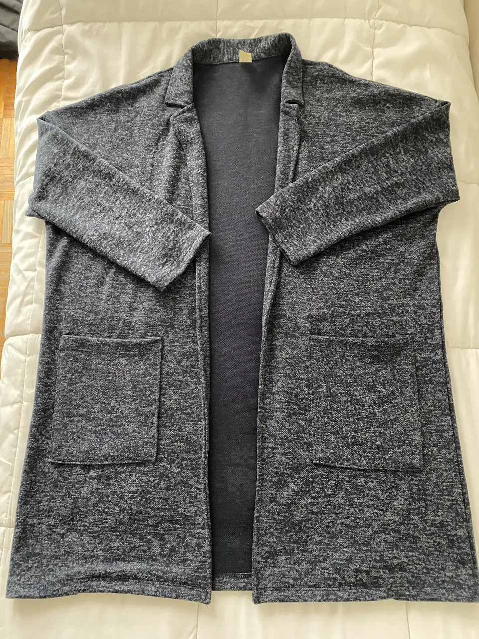 Cardigan largo de mujer en color azul jaspeado, con dos bolsillos delanteros y solapas. Ideal para un look casual y cómodo.