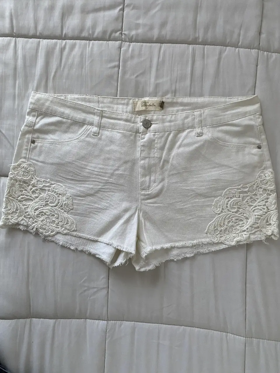 Short de jean blanco tiro bajo con detalles de encaje en los laterales. Talle 42, ideal para un look casual y fresco.