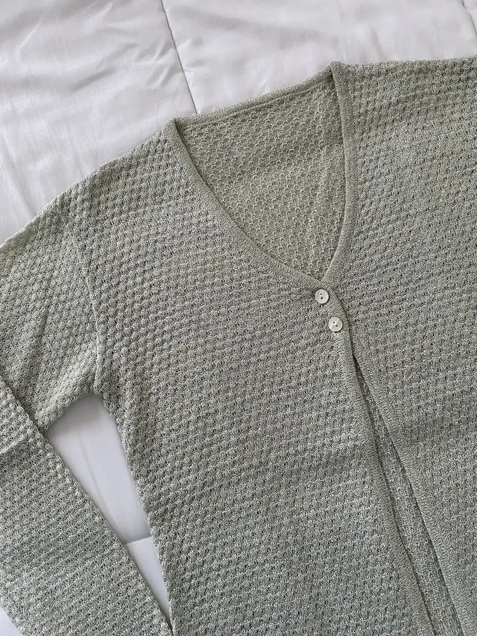Cardigan de mujer en color gris claro, tejido con diseño de rombos brilloso. Ideal para un look casual y cómodo.