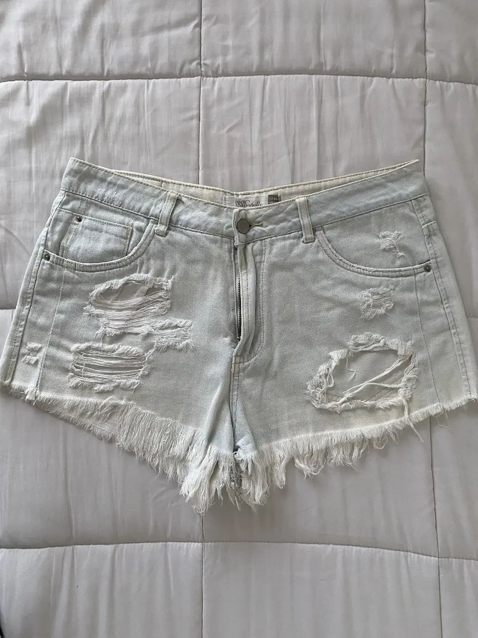 Short de jean de mujer, tiro bajo, con roturas y flecos en el borde. Ideal para un look casual y fresco.