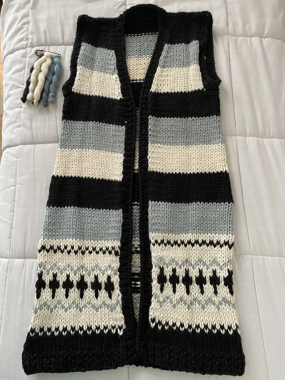Chaleco tejido a mano con diseño a rayas y detalles geométricos, con accesorio prendedor. Ideal para un look casual y abrigado. 
