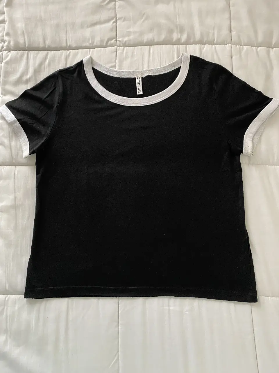 Remera negra de manga corta con detalles en blanco. Cuello y mangas con borde blanco. Ideal para un look casual y cómodo.