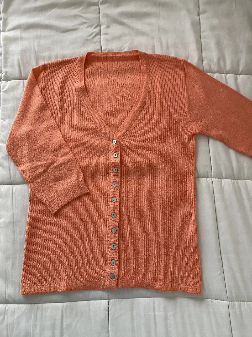 Cardigan de punto color salmón, con botones nacarados y mangas 3/4. Ideal para un look casual y cómodo.