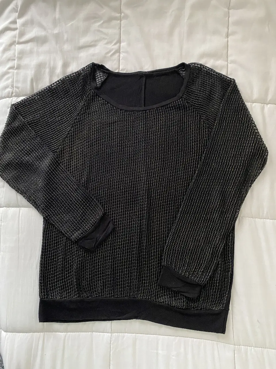 Remera manga larga negra con diseño de red y detalles en dorado, ideal para un look moderno y versátil. Perfecto para combinar con diferentes outfits.