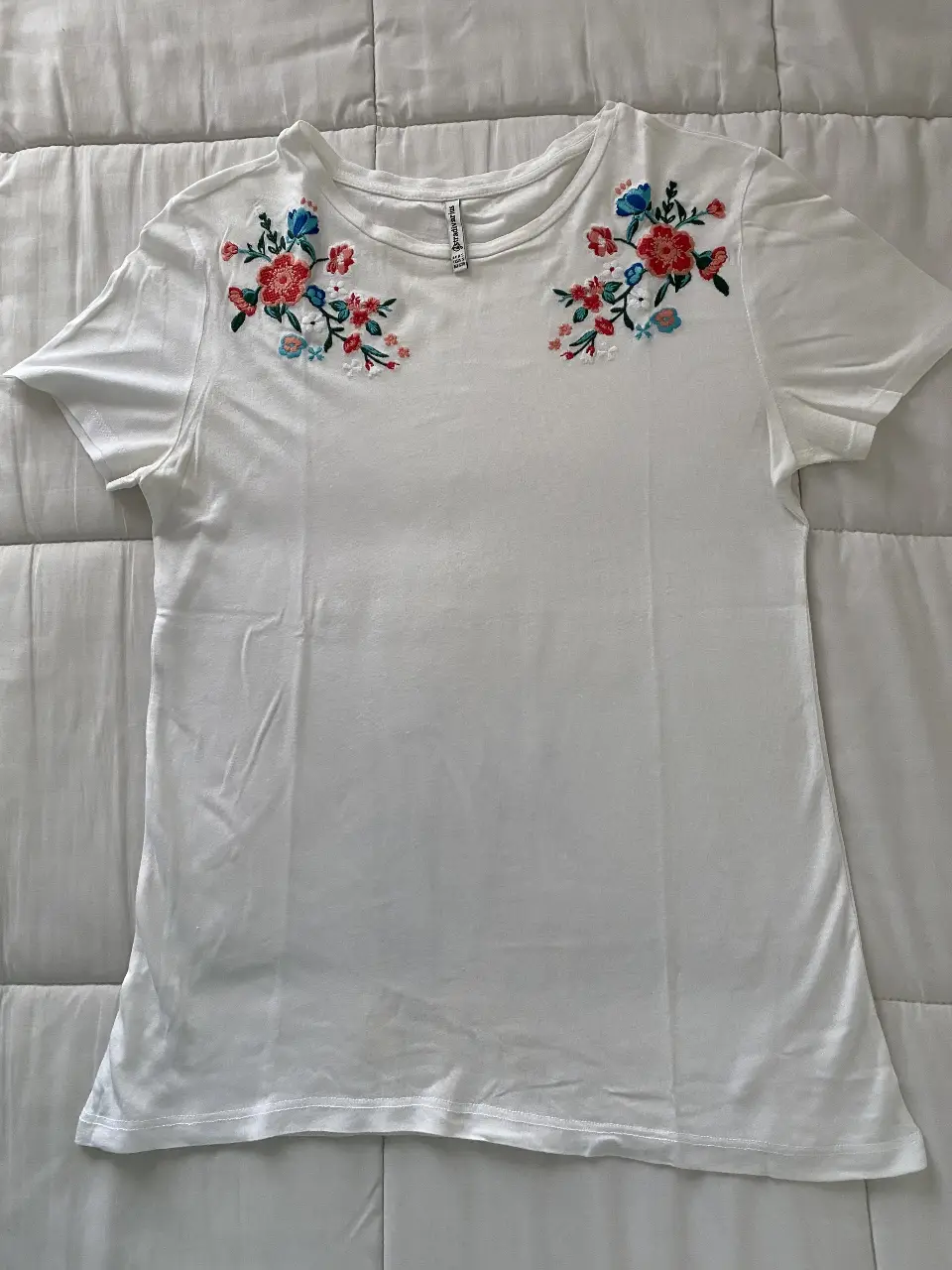 Remera blanca de mujer con bordado floral en la parte delantera. Ideal para un look casual y fresco.