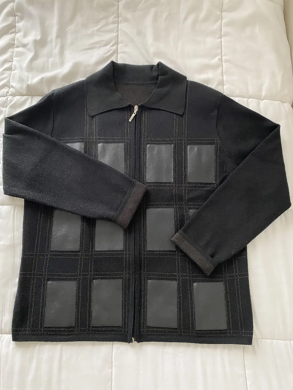 Cardigan negro con detalles de cuero en forma de cuadrados. Cierre frontal y cuello tipo camisa, con hombreras. Ideal para un look casual y elegante.