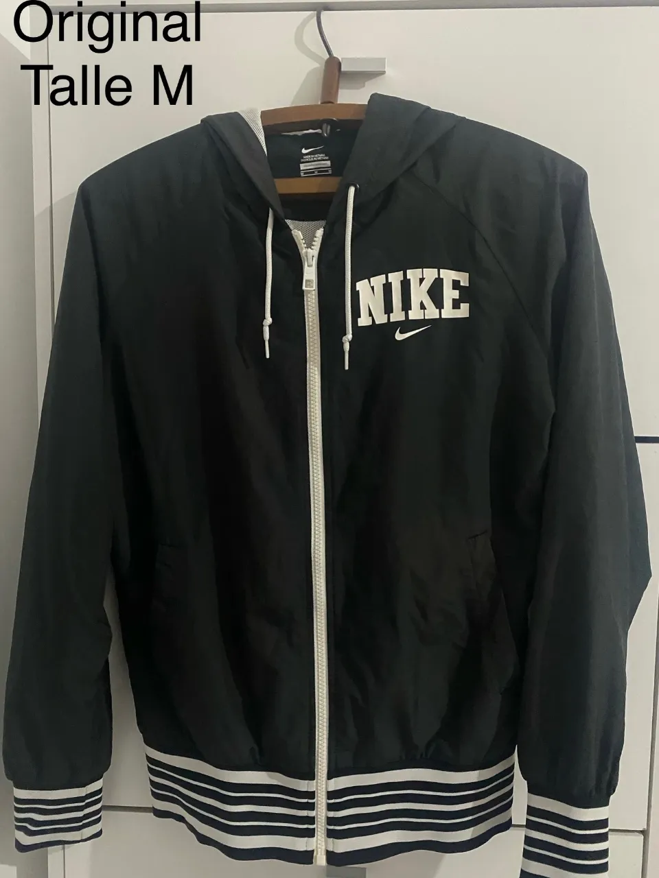 Campera deportiva original negra con capucha y cierre. Posee logo de la marca en blanco en el frente y detalles de franjas blancas y negras en puños y cintura. Ideal para un look casual y deportivo.