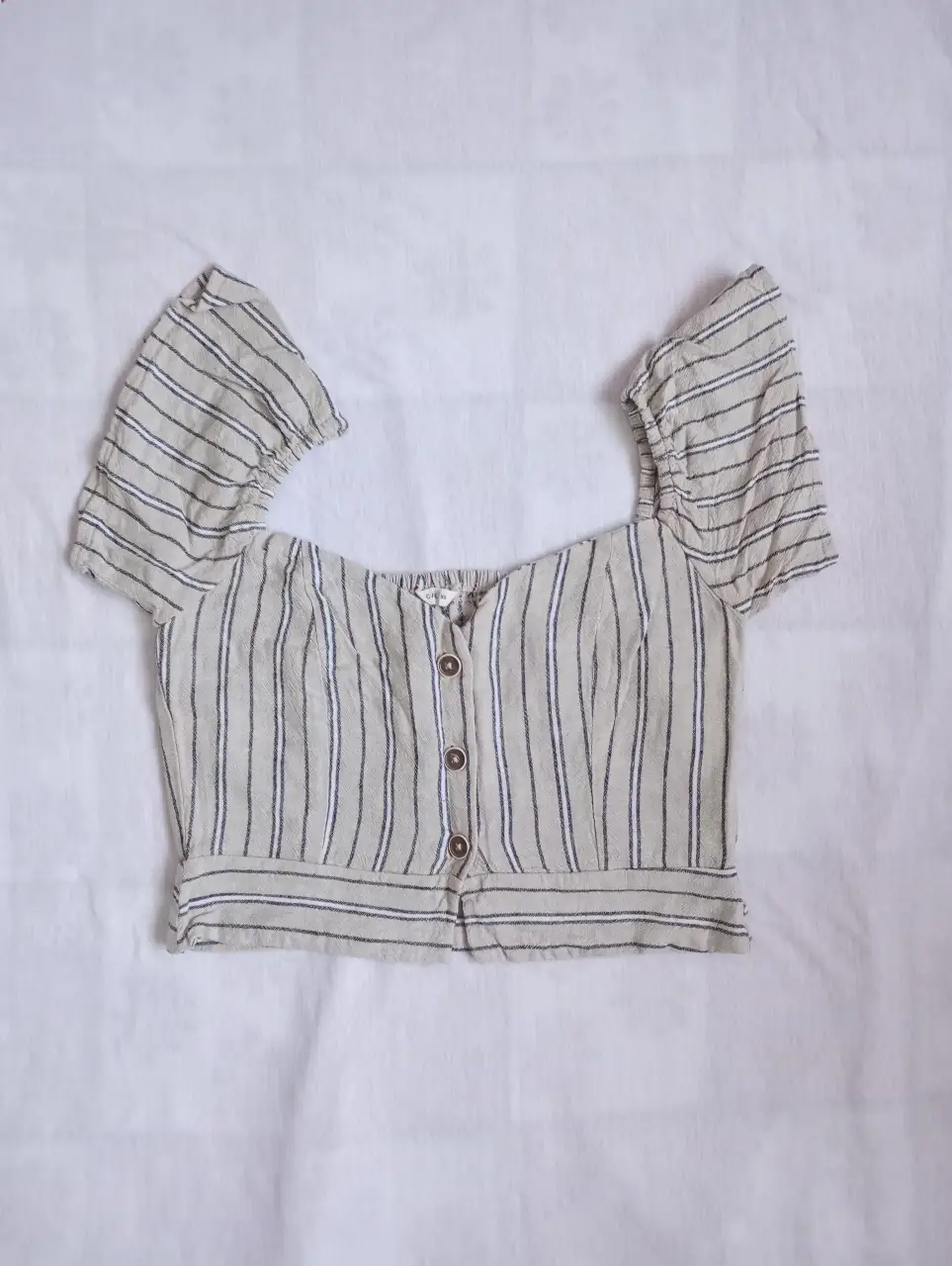 Blusa de mujer a rayas con mangas cortas abullonadas y botones frontales. Ideal para un look casual y fresco.