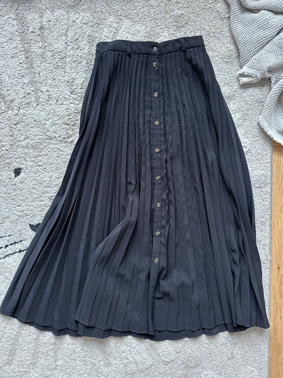 Pollera midi negra de Stradivarius, con botones delanteros y corte plisado. Ideal para un look elegante y versátil.